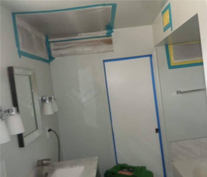 Bathroom with white walls and containment tarp sealing all openings to the room including air vents