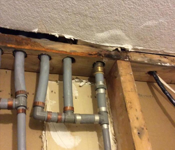water pipes within the framing of a wall are exposed as well as the studs